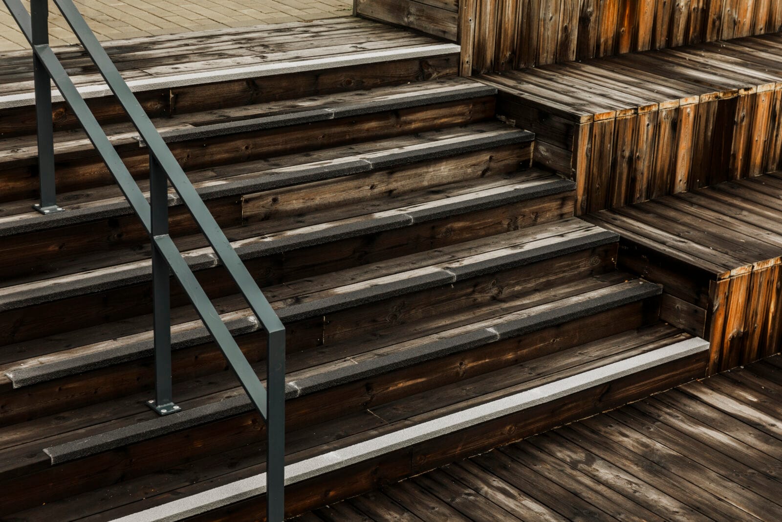 Svarta oh grå trappnoslister i glasfiber på blöt trätrappa utomhus