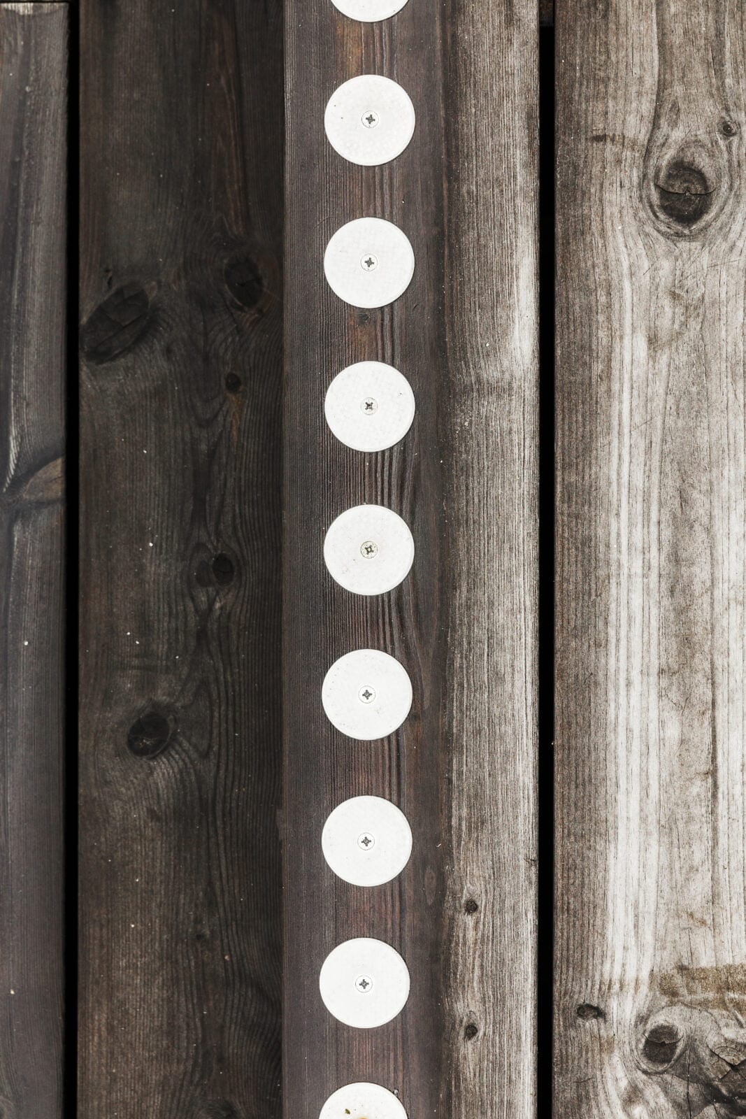 Vita kontrastprickar med skruvhål på trappa i trä utomhus